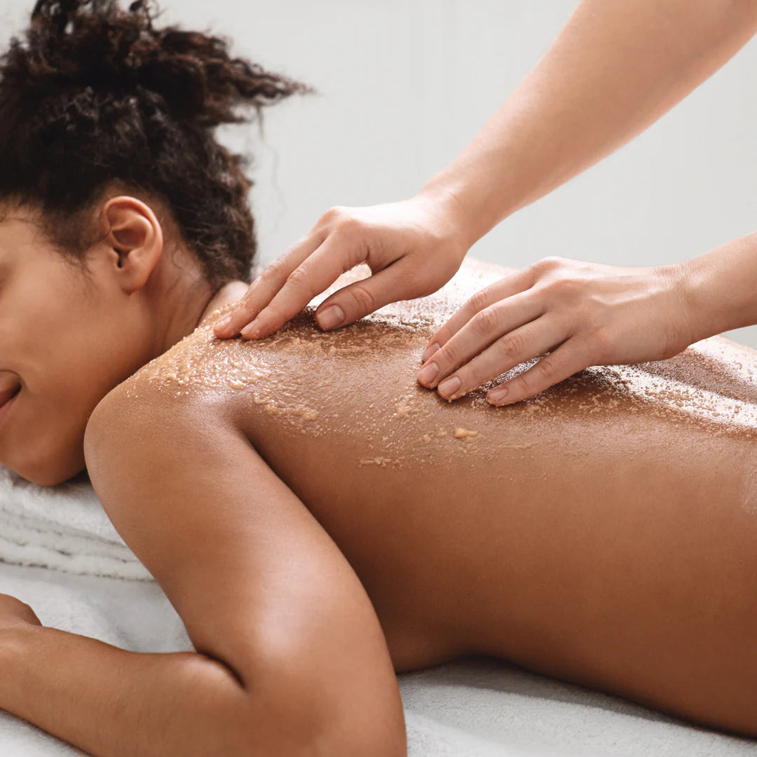 Hands massaging Himalayan salt scrub into the skin at a spa