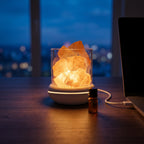 Salt glow lamp glowing at dusk beside a laptop with city lights behind