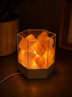 Modern Himalayan salt lamp casting a warm amber glow in a dark room, USB cord visible