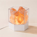 Modern Himalayan salt lamp with real pink salt chunks glowing in a clear hexagonal case on a white base