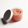 Open jar of Himalayan salt body scrub with coral-pink exfoliating salt grains
