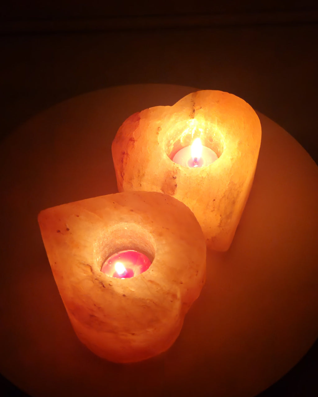 Two heart shaped salt candle holders lit together