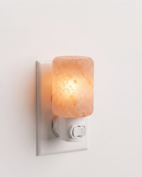 Himalayan salt crystal wall lamp plugged into a white outlet, glowing warm amber