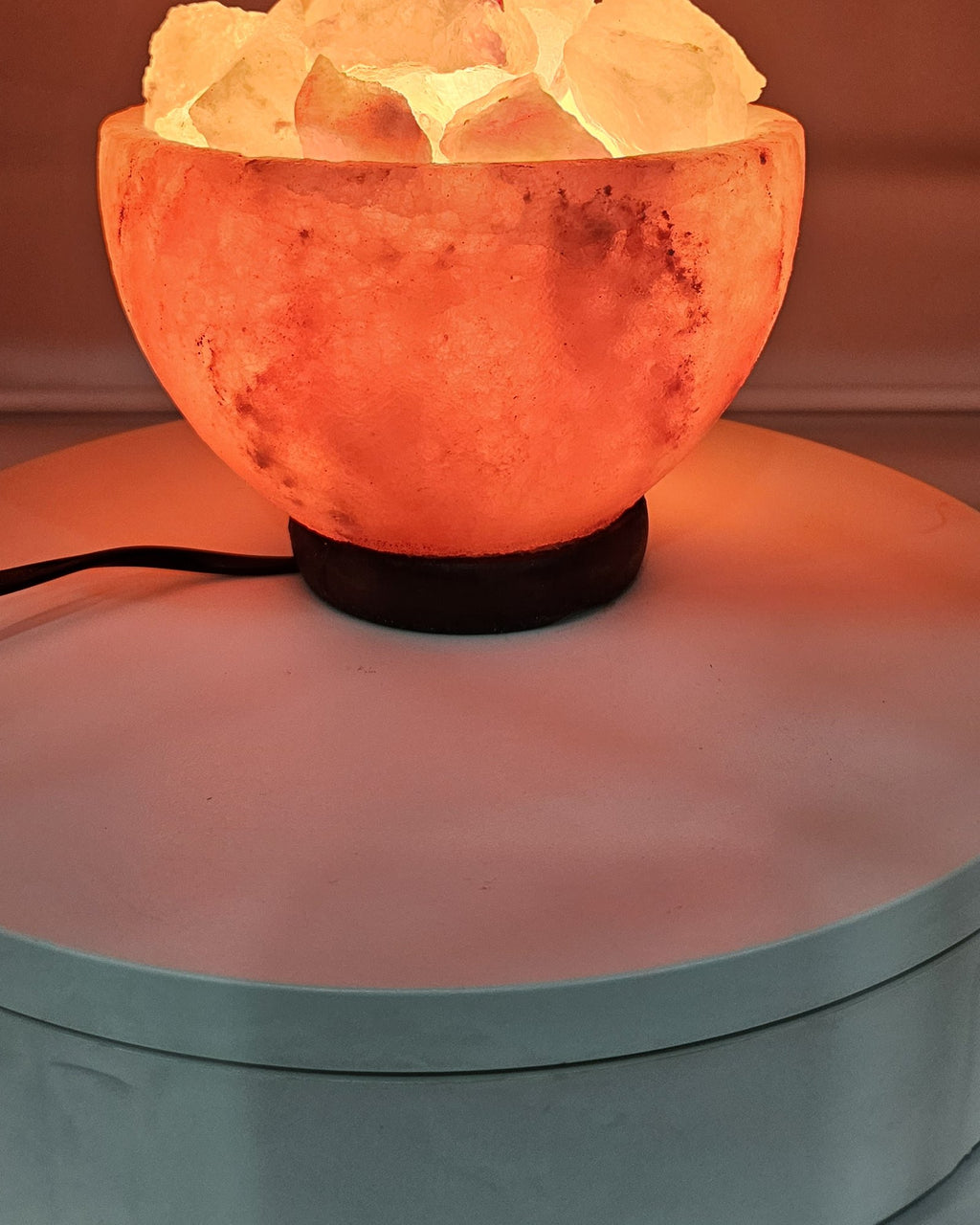 Himalayan salt bowl lamp lit, filled with loose salt chunks