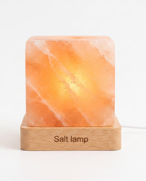 Himalayan salt night lamp with a hand-carved wooden base glowing warm amber on a white background