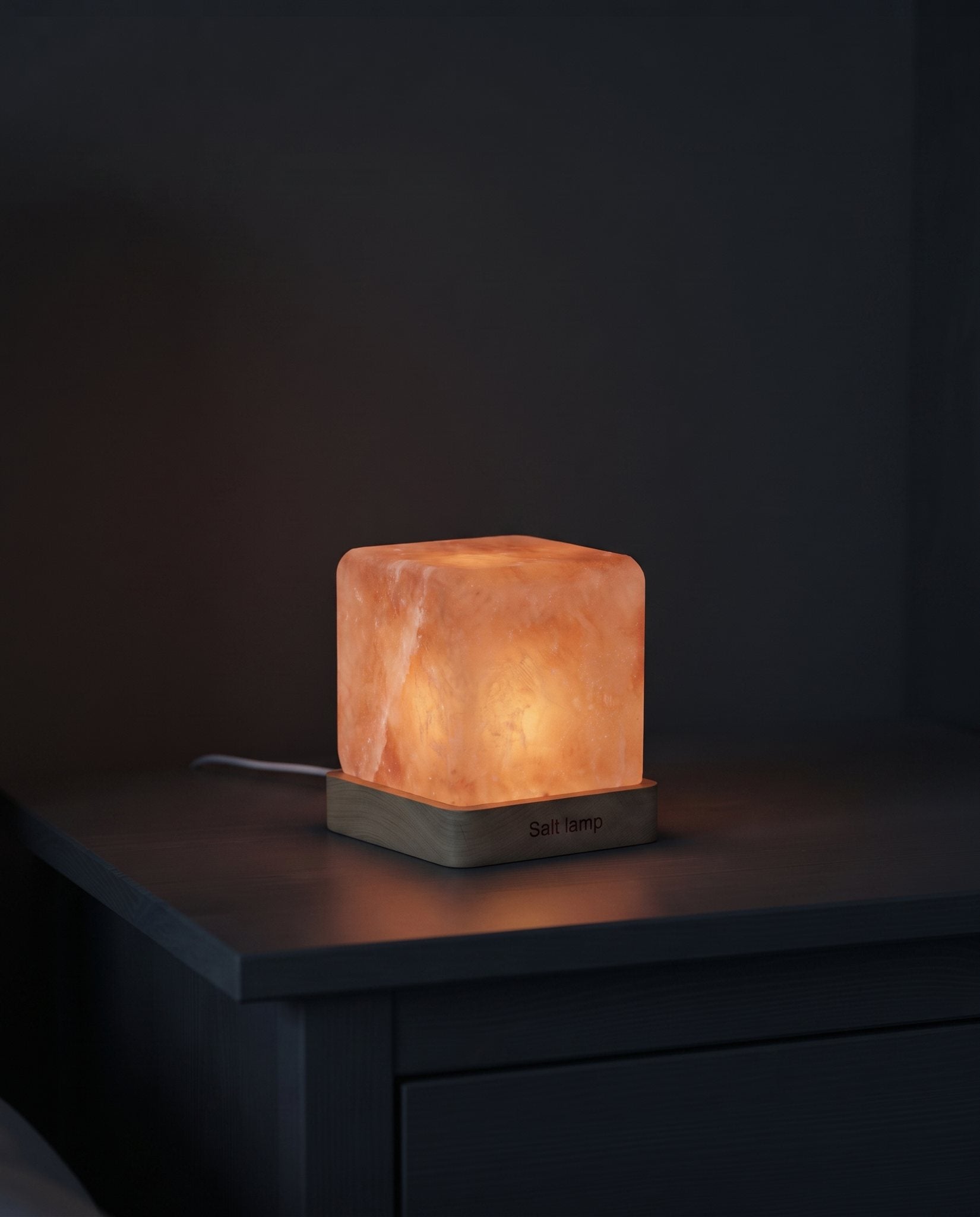 Himalayan salt night lamp casting a warm amber glow in a dark bedroom