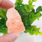 Real photo of a rough Himalayan salt rock chunk held between fingers