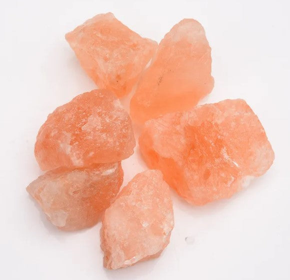 Six rough uncarved orange rock salt chunks on a white background