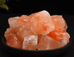 Close up of rough orange and white salt crystals filling a dark dish