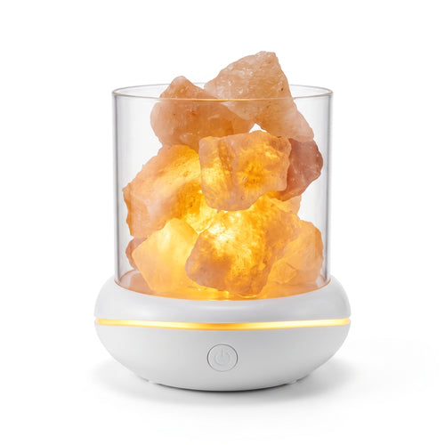 Himalayan salt glow lamp switched on, warm amber light through pink salt chunks on a white base