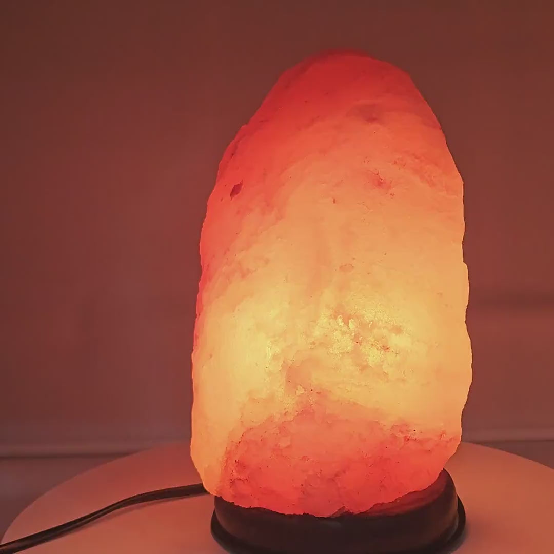 The hand-carved salt lamp glowing warm amber, rotating