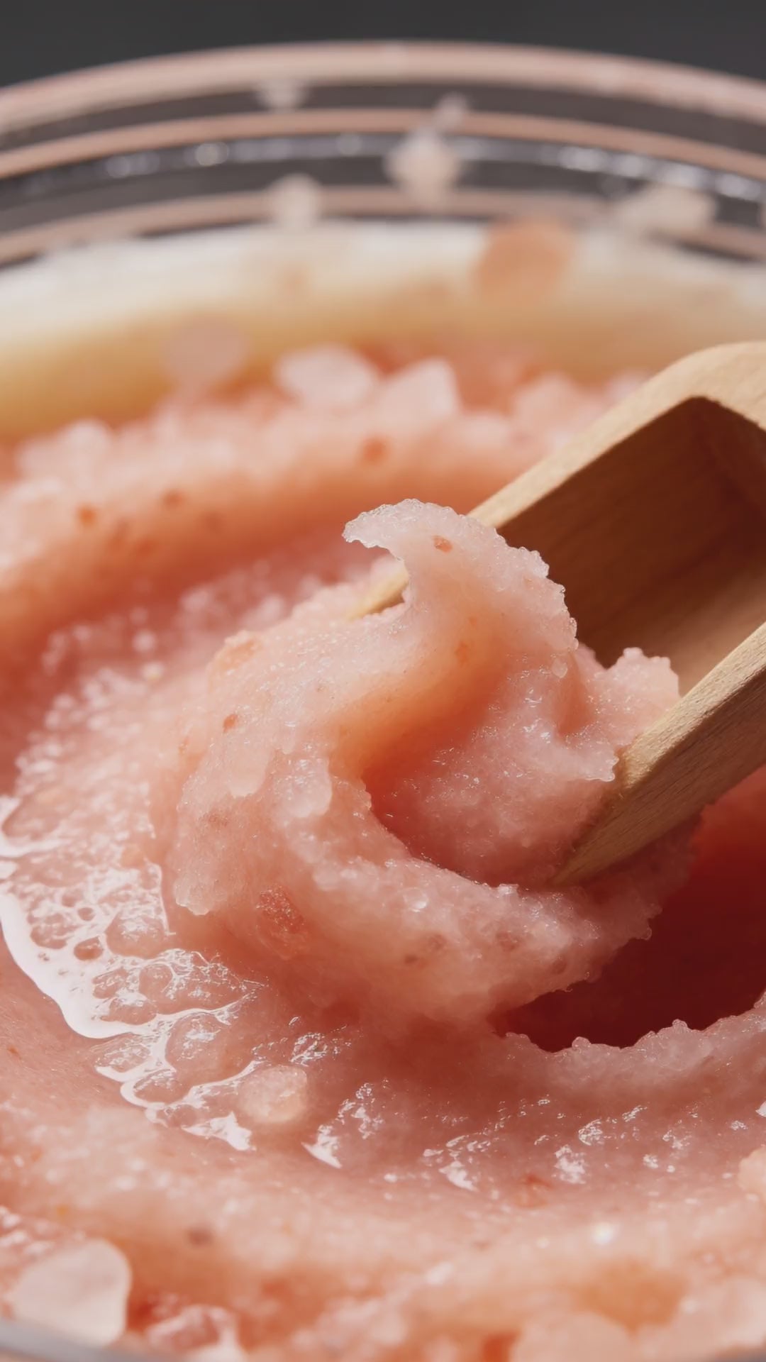 Wooden scoop lifting a soft curl of Himalayan salt body scrub