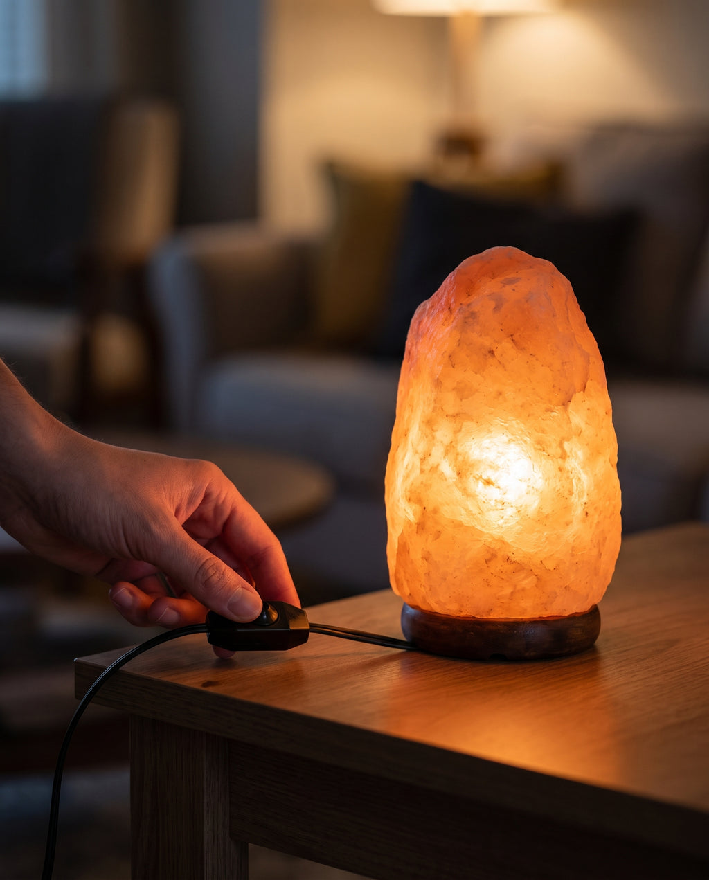 Fingertips on the inline rotary dimmer wheel, the lamp glowing behind