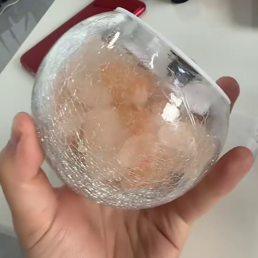 Angled view of the lamp in hand, showing the crackle texture across the clear glass dome