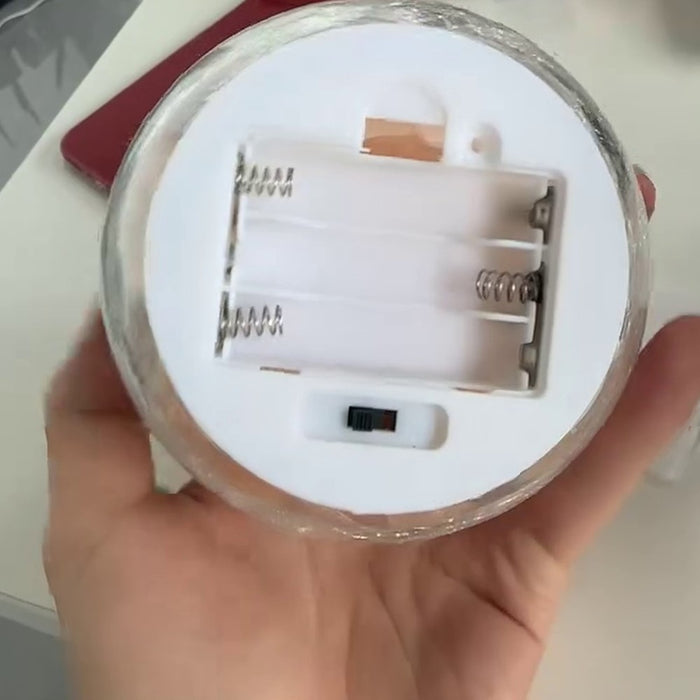 Underside of the white base showing the open three AAA battery compartment and the sliding on and off switch, batteries not included