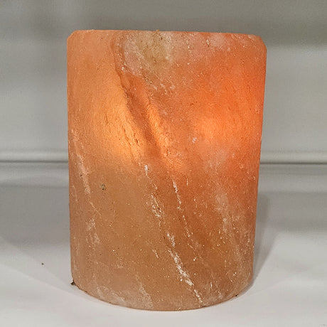 Cylinder Himalayan salt tea light holder, a smooth turned column, lit from within so the glow shows through the wall of the stone