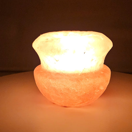 Gourd Himalayan salt tea light holder, a squat urn flaring to an open cup, lit, the rim and body glowing