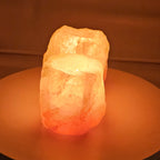 Natural Himalayan salt tea light holder with one well, lit, the stone glowing from the inside