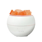 Mini salt humidifier unlit on a white background: white sphere with a ring of rough pink Himalayan salt pieces around the top opening