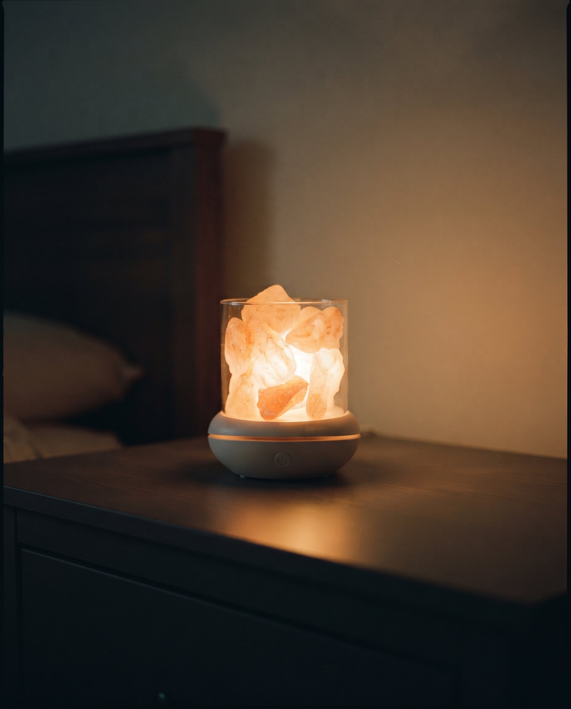 Salt glow lamp casting a warm amber glow in a dark bedroom