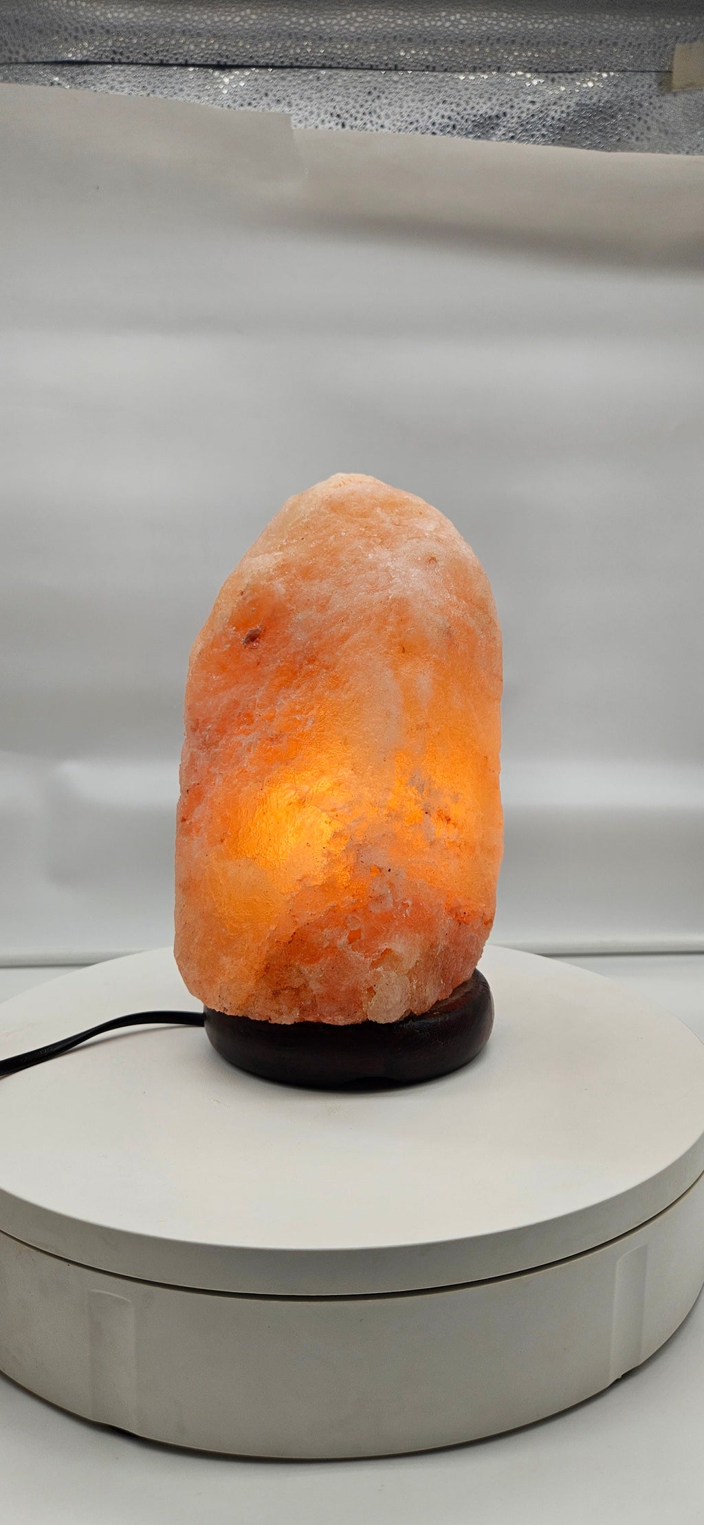 The real lamp lit warm on a white table, customer-style photo
