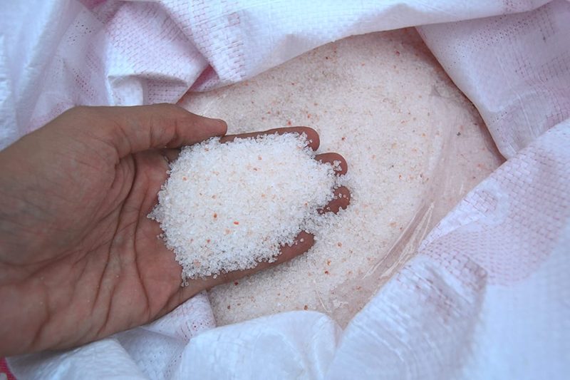 A hand holding raw pink Himalayan salt at the source