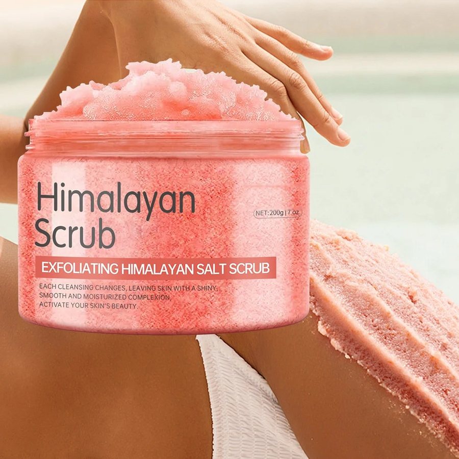 The real Himalayan salt body scrub jar, piled with pink salt scrub, held beside skin