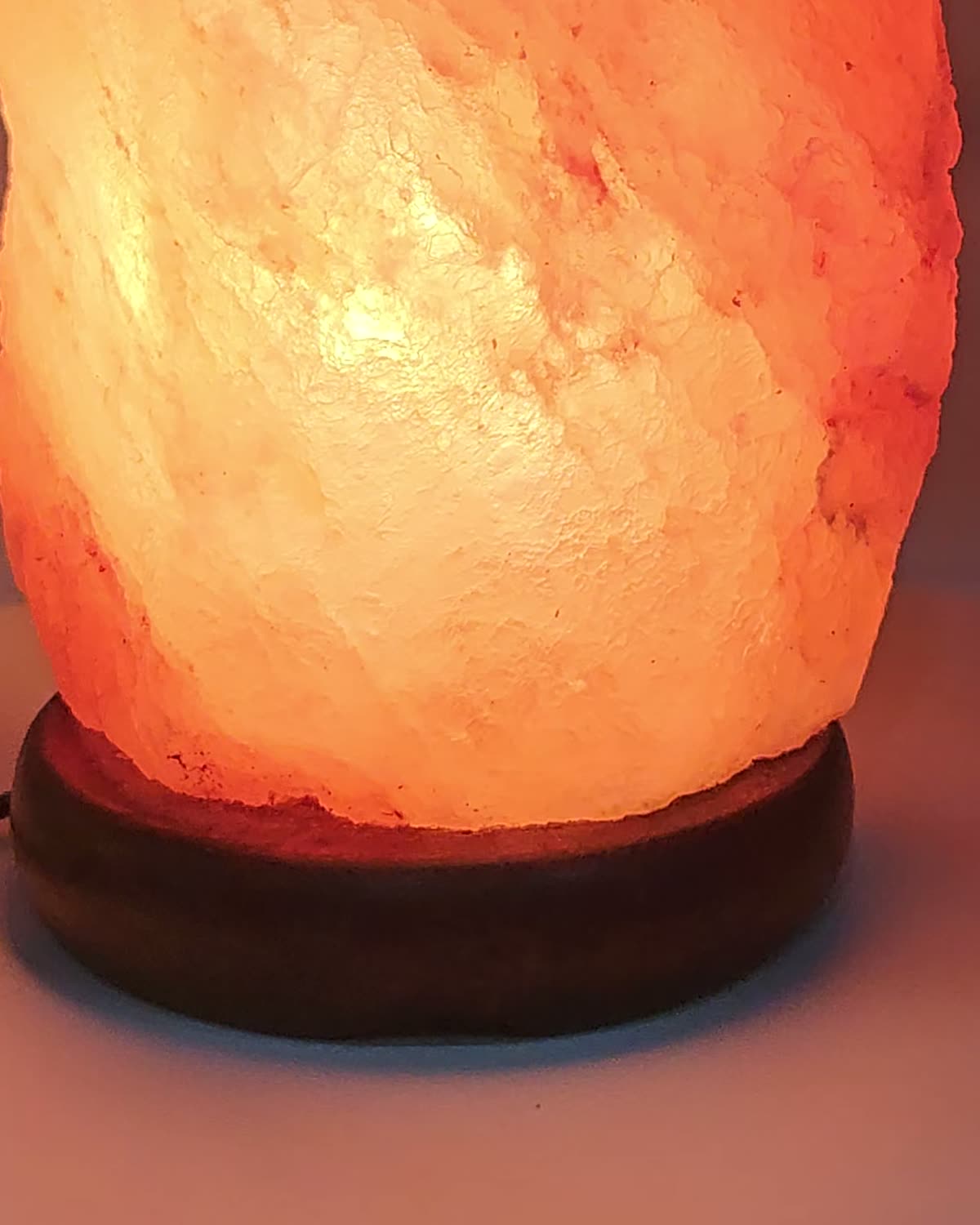 The round dark-stained wooden base under the salt crystal